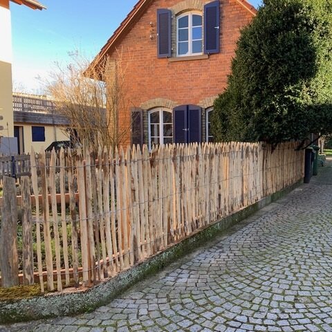 Staketenzaun auf Mauer Steinhaus mit Garten und Pflaster